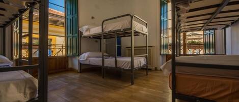 Un dormitorio con literas, suelo de madera y vistas al balcón exterior.