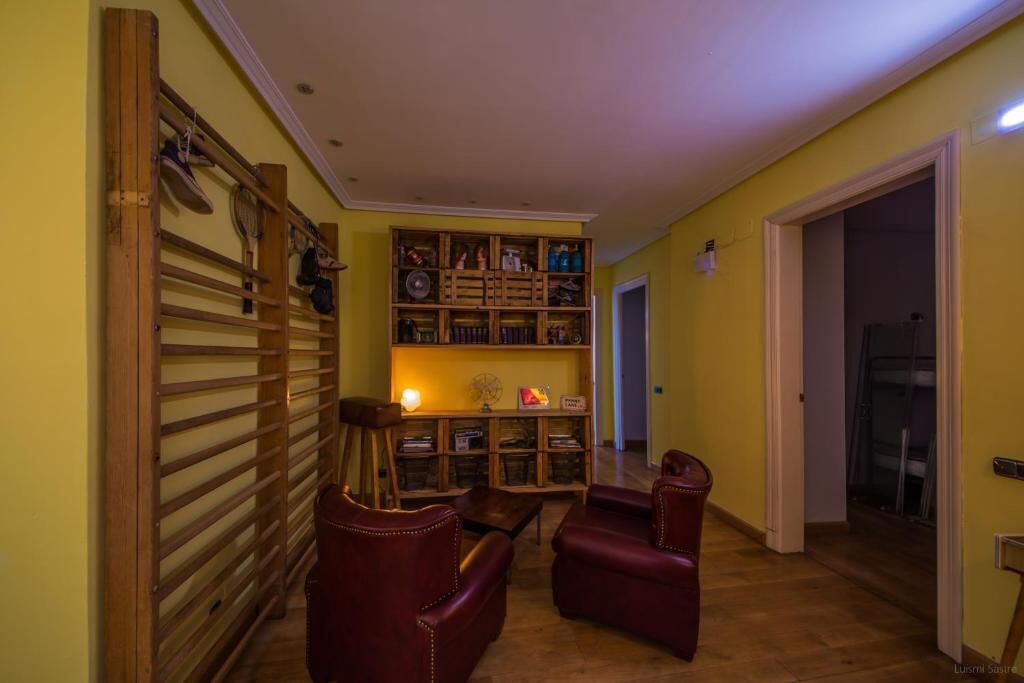 Un salon chaleureux avec une bibliothèque en bois, deux fauteuils en cuir et une petite table.