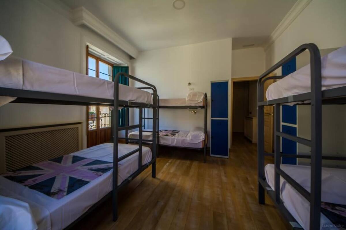 Un dormitorio con literas, una ventana con cortinas y una puerta que da a otra habitación.