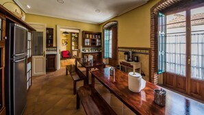 A kitchen with wooden cabinets, a refrigerator, a dining table with benches, and a window with a view of the outside. - Hostel Covent Garden by gaiarooms  (León)