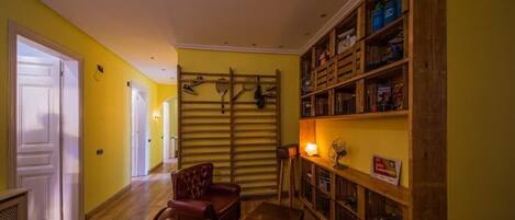 A hallway with a wooden chair, a small table, and a bookshelf filled with books and items.