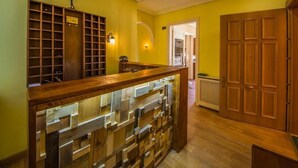 A room with a wooden bench, a shelf with shoes, and a door with a sign. - Hostel Covent Garden by gaiarooms  (León)