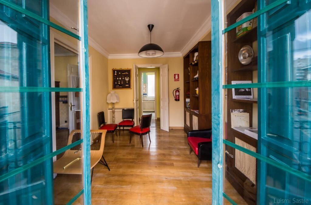 Ein Zimmer mit Holzboden, einem Esstisch mit Stühlen, einem Bücherregal und einer Tür mit Glasfenstern.