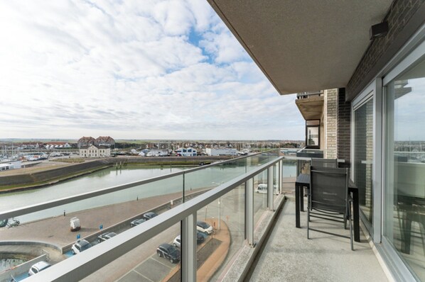 A balcony with a view of a river and distant buildings.