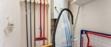 A utility room with cleaning equipment, a vacuum cleaner, and a storage rack.