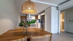 Un comedor moderno con una mesa de madera, sillas de mimbre y una lámpara colgante.