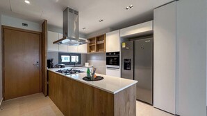 Una cocina moderna con una isla central, electrodomésticos de acero inoxidable y una puerta de madera.
