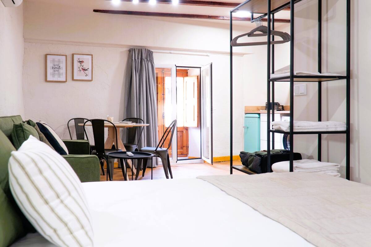 Een hotelkamer met een bed, een bureau met stoel, een kledingkast en een ophangrek met handdoeken.