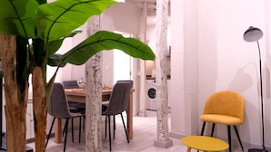 Un comedor con mesa de madera, sillas y una lavadora al fondo.