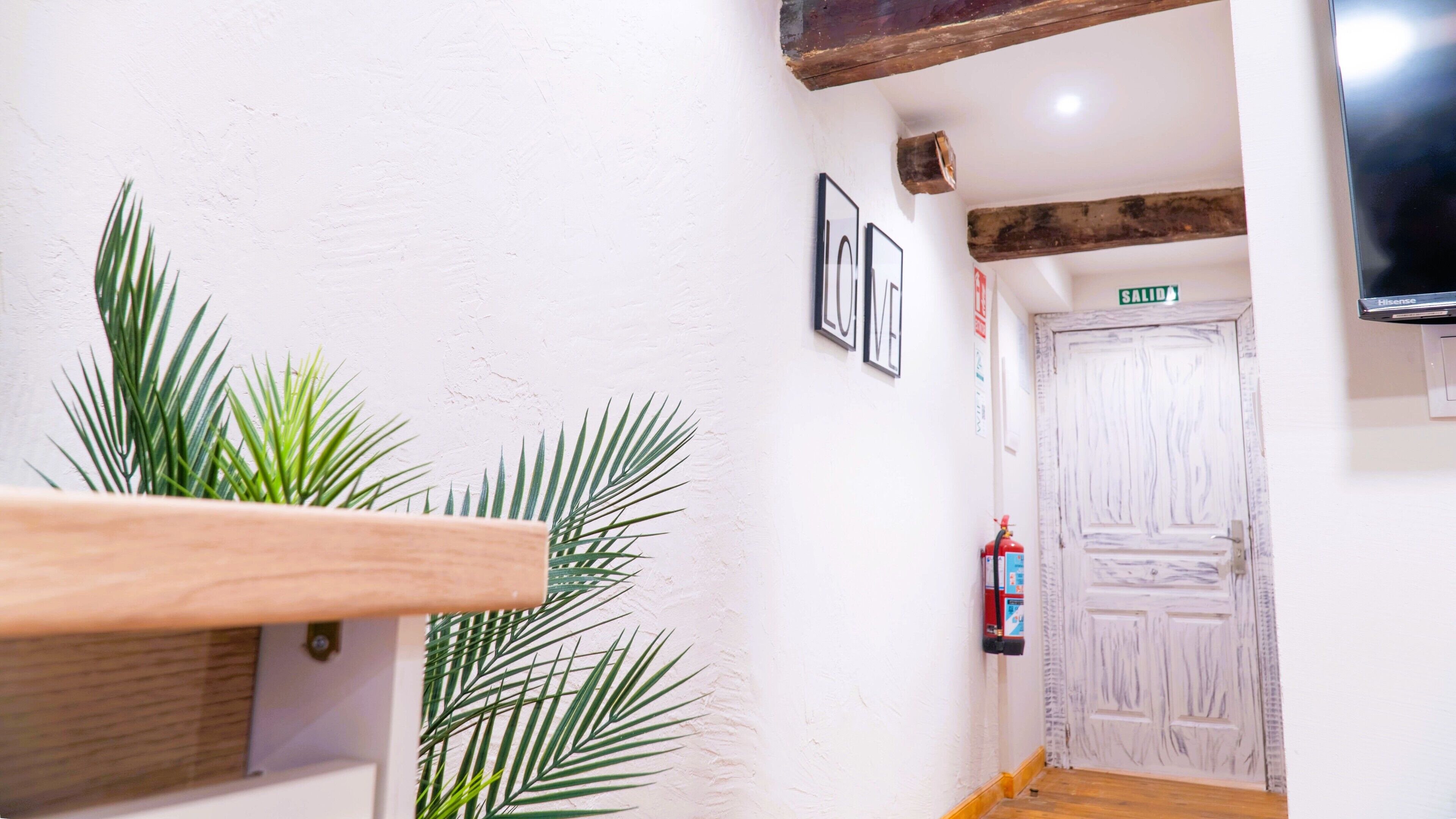 A hallway with a wooden handrail, a fire extinguisher, and a door labeled "SALIDA".