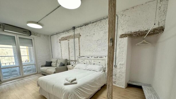 Un dormitorio con cama, mesita de noche, cómoda y lámpara colgante.