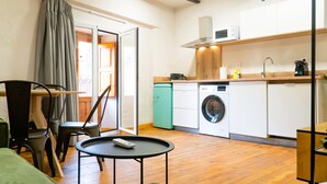 Cocina compacta con lavadora, microondas y una pequeña zona de comedor con mesa y sillas.