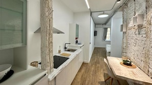 Una cocina moderna con encimera de mármol, suelo de madera y una pared decorativa de ladrillo.