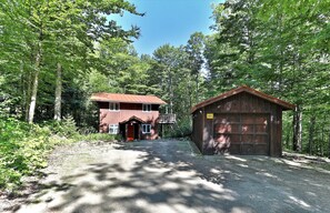 Une cabane rustique avec une façade en bois, un toit en métal et un petit garage attenant.