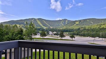 A view from a balcony overlooking a valley with a road leading up a mountain.