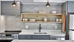 Una cocina moderna con una isla central, electrodomésticos integrados y un salpicadero de azulejos hexagonales.
