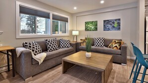 A modern living room with a grey sofa, patterned cushions, a wooden coffee table, and a small plant. - Renovated. Mountain Views. Steps to Killington. Discounted Ski Rentals. 3C16 (Killington)