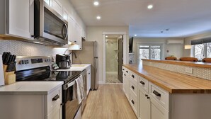 A modern kitchen with white cabinets, a stainless steel stove, and a wooden countertop.