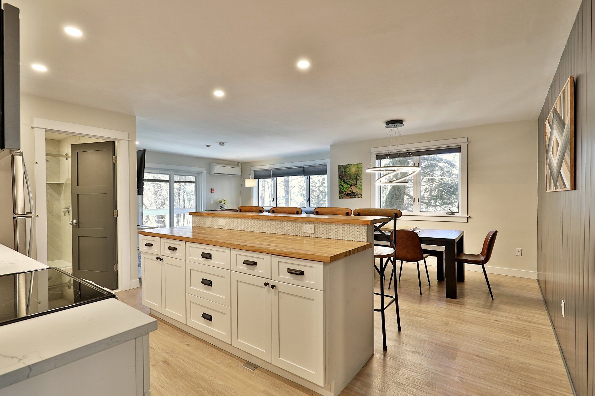 A modern kitchen with a central island, white cabinetry, and a dining area with a wooden table and chairs.