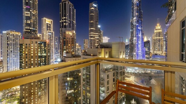 Un immeuble de grande hauteur doté d’un balcon en verre qui offre une vue sur le paysage urbain illuminé la nuit.