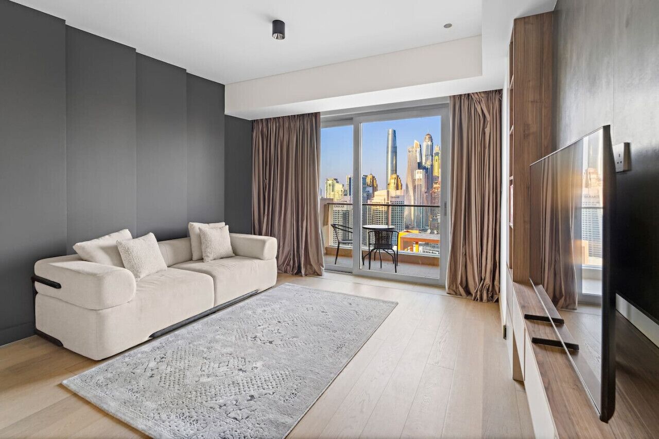A modern living room with a sofa, a large rug, and a TV.