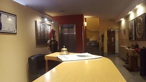 Un pasillo con un escritorio, sillas y un radiador.