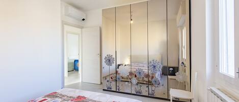A bedroom with a bed, a wardrobe, a chair, and a window.