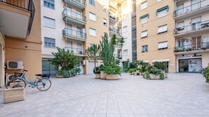Une cour avec un vélo bleu, des plantes en pot et un immeuble doté de balcons.