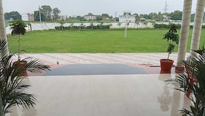 En terrass med utsikt över en grön gräsmatta och byggnader i bakgrunden.