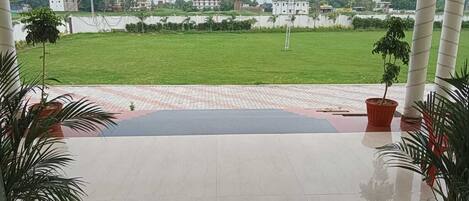 Um terraço com vista para um gramado verde e edifícios ao fundo.