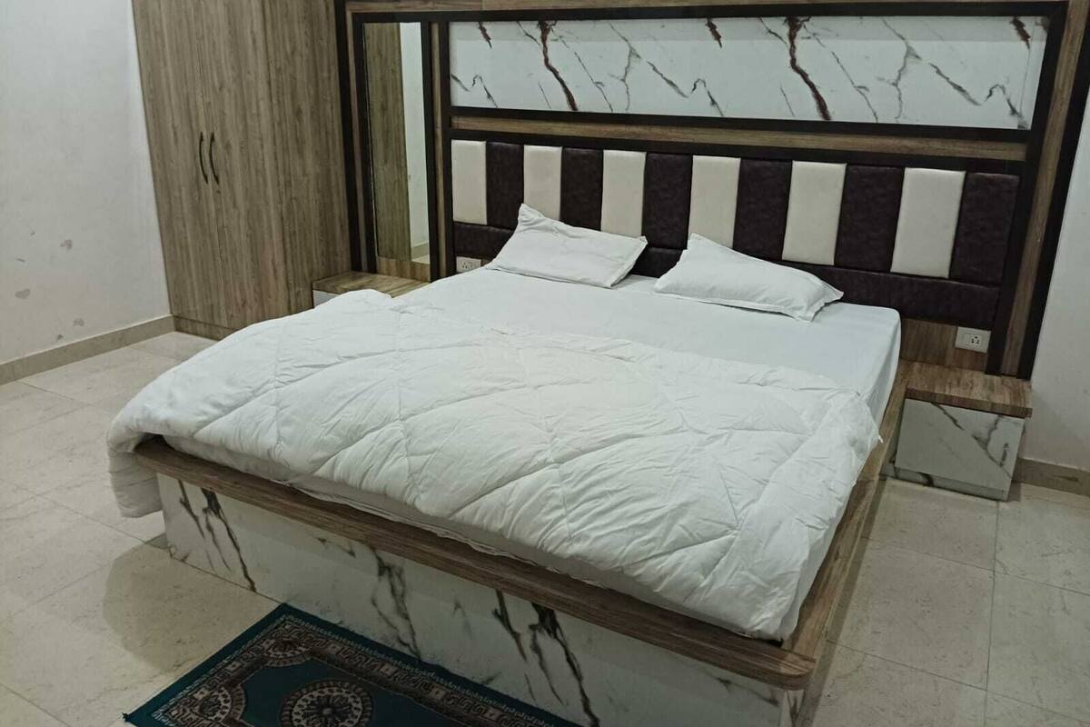 Un dormitorio con cama, armario y alfombra estampada.