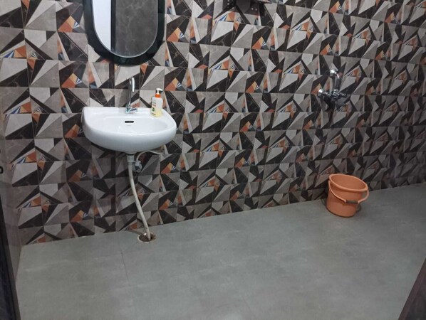 A bathroom with a white sink, a mirror, and a toilet. - Hotel Atharv By GRB (Varanasi)