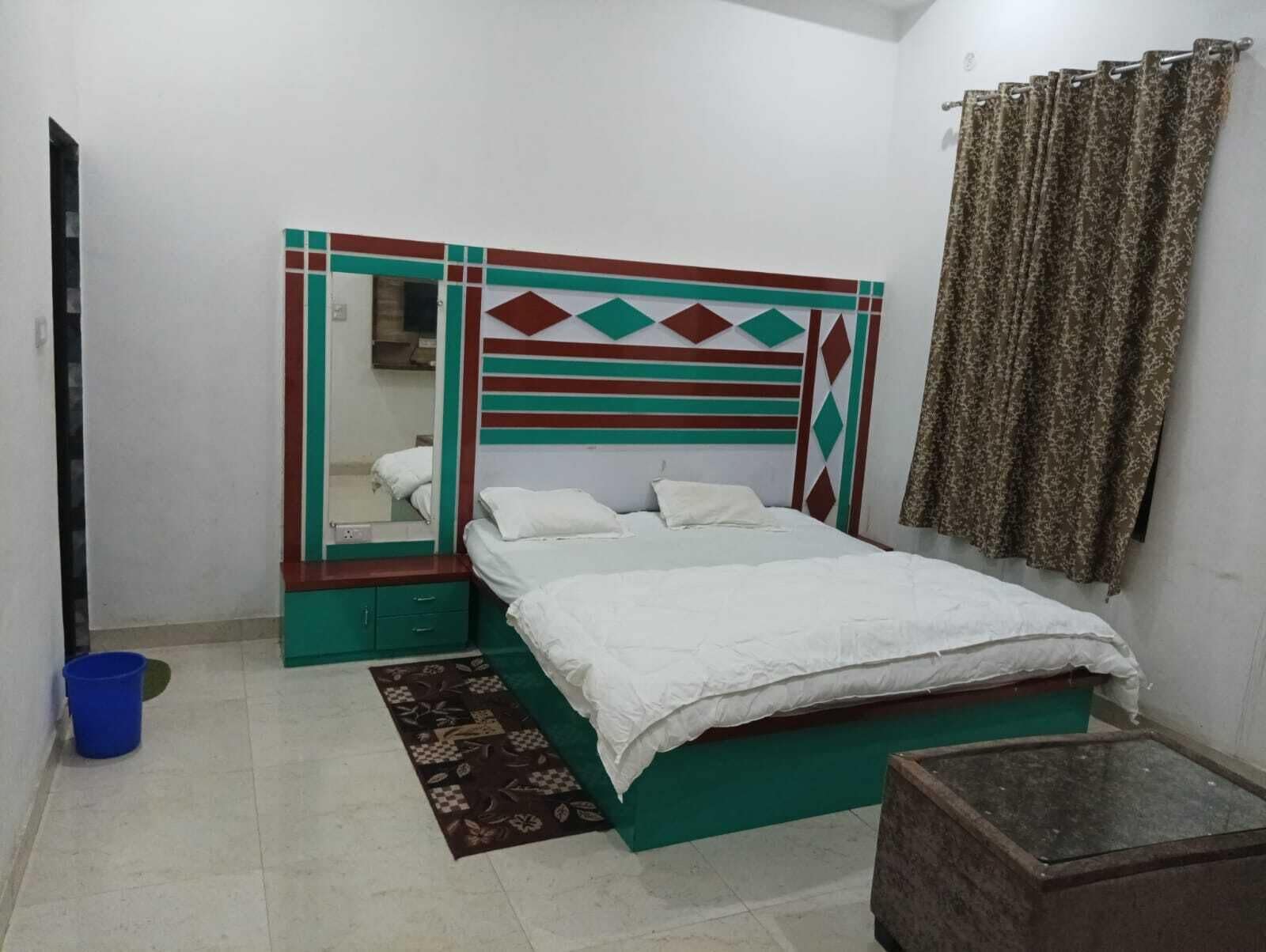 A bedroom with a bed, a dresser, a mirror, and a curtain.