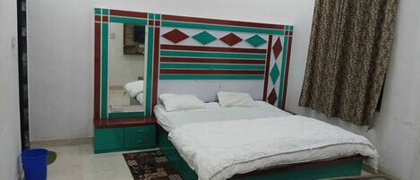 A bedroom with a bed, a dresser, a mirror, and a curtain.