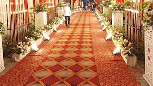 En korridor med ett mönstrat mattgolv, draperade gardiner och blomsterarrangemang.