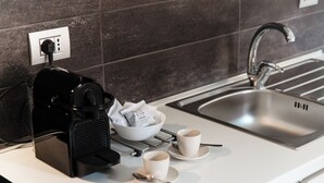 Una cucina moderna con una macchina del caffè, una ciotola di capsule di caffè e due tazze su un piano di lavoro.