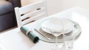 A dining table with a white plate, a wine glass, and a rolled napkin.