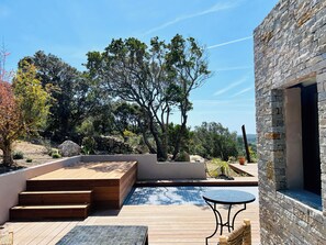 A modern outdoor patio with wooden steps, a round table, and a stone wall.