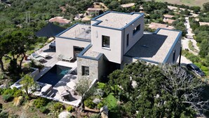 Une maison moderne à deux étages, dotée d’une piscine, de mobilier d’extérieur et d’un jardin.