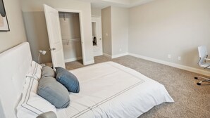 A bedroom with a large bed, a ceiling fan, and a walk-in closet.