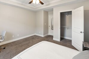 Relax in this serene bedroom with a large bed, ceiling fan, and comfortable chair.