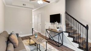 A living room with a sofa, coffee table, and a TV on the wall.
