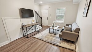 A living room with a sofa, coffee table, and TV mounted on the wall.