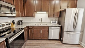 A modern kitchen with wooden cabinets, stainless steel appliances, and a granite countertop.