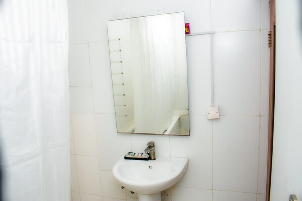 A bathroom with a white sink, a mirror, and a towel rack. - EED Pension Boutique Hotel (Lagos)