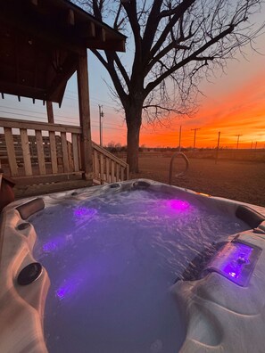 A hot tub with a wooden deck and a tree in the background.