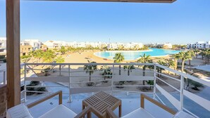 A balcony with a view of a beach, pool, and resort buildings. - El Gouna - BIRD NEST (El Gouna)