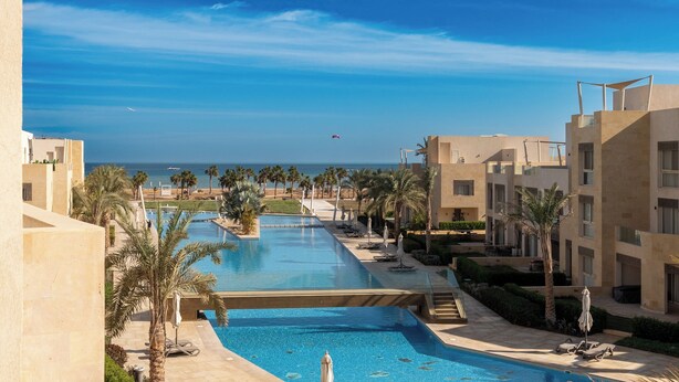 A resort with a large swimming pool, palm trees, and a view of the ocean. - El Gouna - BIRD NEST (El Gouna)