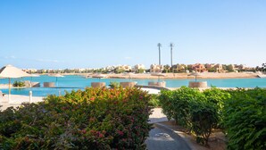 A coastal resort with a clear view of the sea, a paved walkway, and lush greenery. - El Gouna - BIRD NEST (El Gouna)