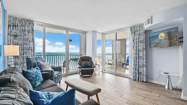 Ein geräumiger Balkon mit Meerblick, ausgestattet mit einer Couch, Stühlen und einem kleinen Tisch.